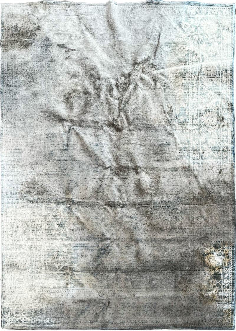 A heavily soiled and stained light blue area rug before being professionally cleaned by Wooden Looms in Austin, TX.