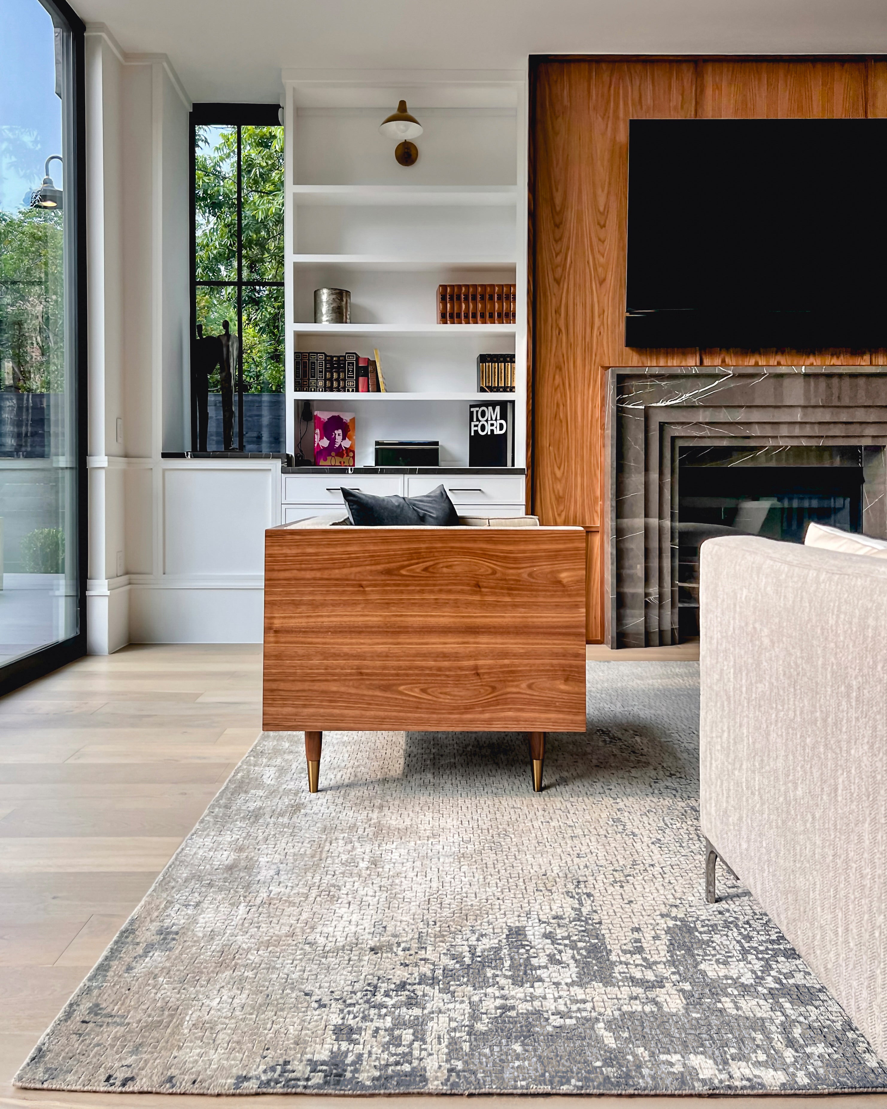 A contemporary abstract rug in grey and cream tones, featured in a Wooden Looms project in a sophisticated Austin, TX living room with a mid-century modern console and marble fireplace.