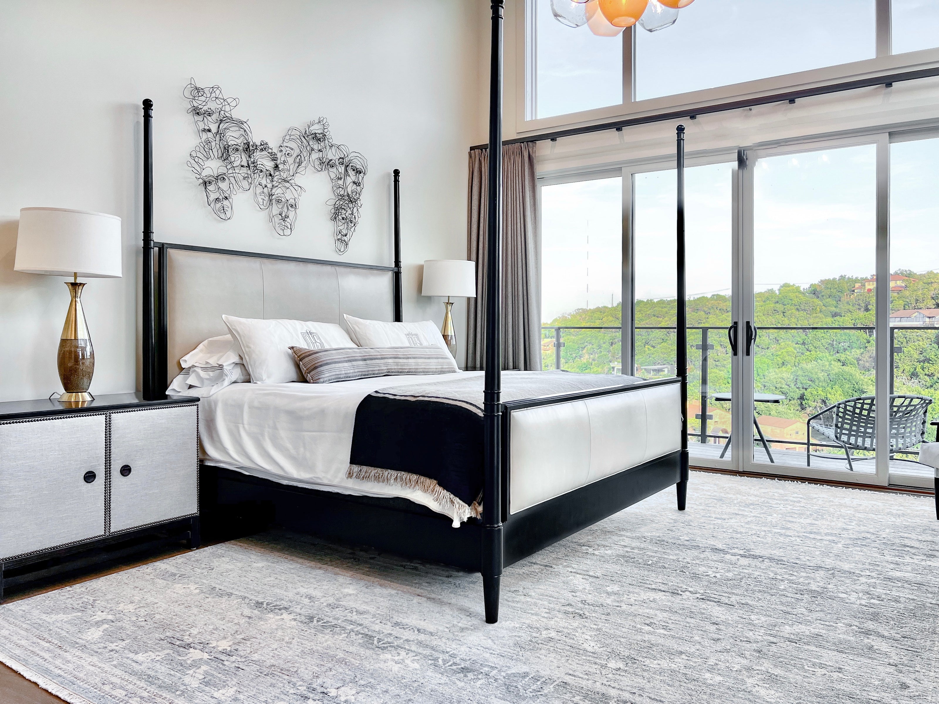 A large vintage look rug in a blue haze color with a subtle abstract pattern, featured in a Wooden Looms project in a luxury Westlake bedroom with a black four-poster bed.