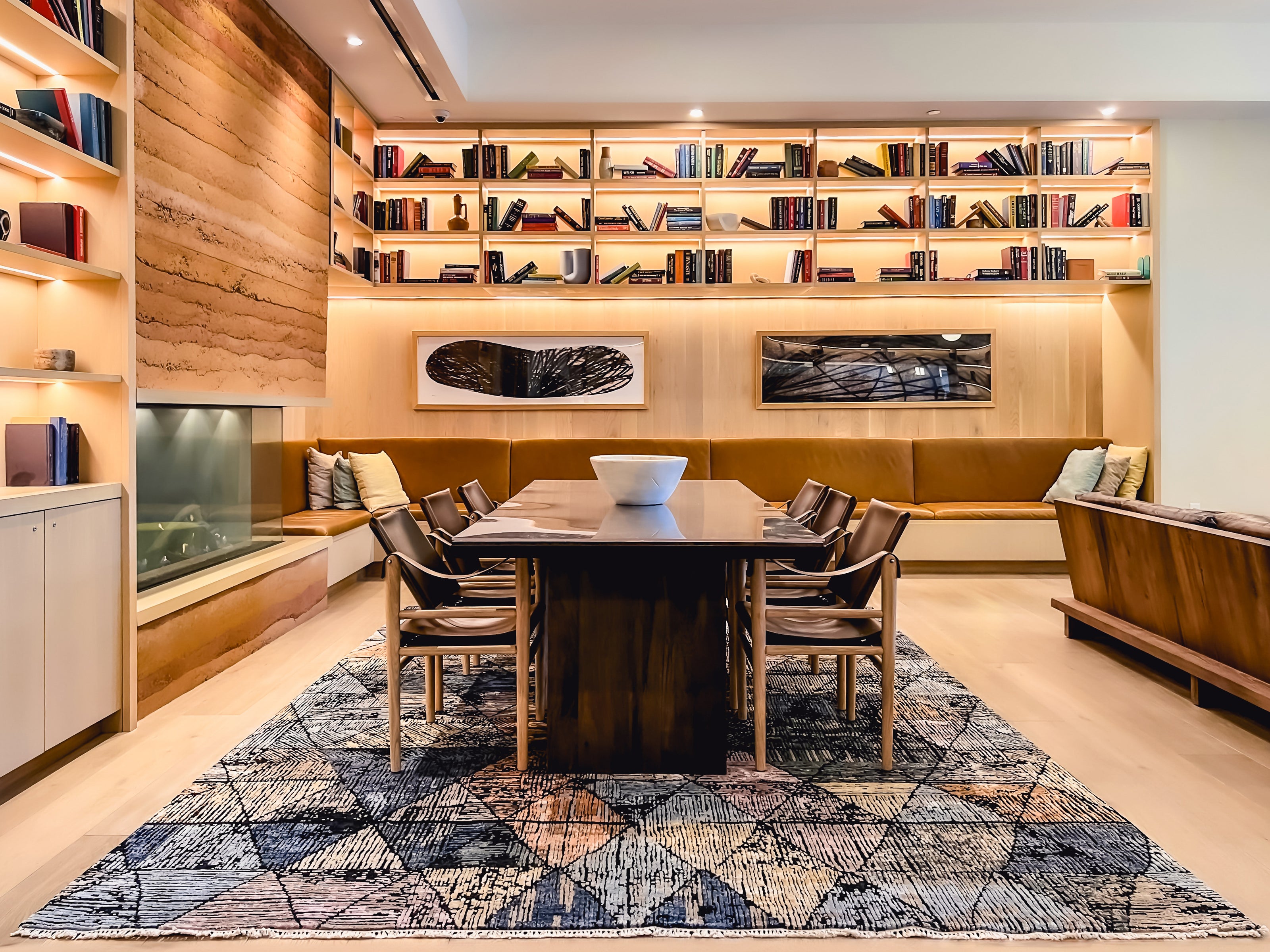 A large modern geometric rug with a blue and rust triangle pattern, featured in a Wooden Looms commercial project in an Austin, TX lobby and library space.